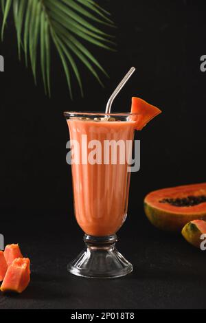 Lassi asiatique de papaye sur fond noir. Boisson fraîche froide de yaourt, eau, épices, fruits et glace. Boisson populaire en Inde et au Sri lanka. Ver Banque D'Images