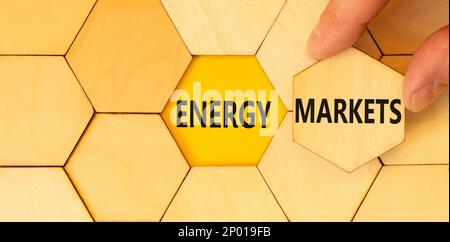 Symbole marchés de l'énergie. Concept mots marchés de l'énergie sur des puzzles en bois. Magnifique table jaune fond jaune. Main d'homme d'affaires. Énergie des affaires mar Banque D'Images