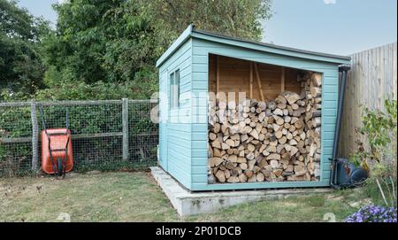 Brouette orange et abri ouvert avec une pile de bois de feu séché, pour brûler Banque D'Images