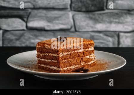 Dessert tiramisu sur fond sombre. Tranche de gâteau au café décorée de grains de café. Dessert italien crémeux traditionnel sur la table dans le café-restaurant. Banque D'Images