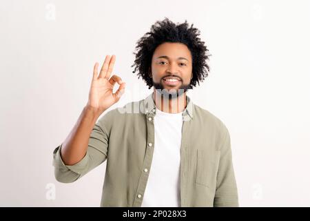 Charismatique gai mauriquement africain américain homme 30s montrant OK geste en signe g approbation et accord se tenant isolé sur fond blanc, gars démontrant que tout sous contrôle Banque D'Images