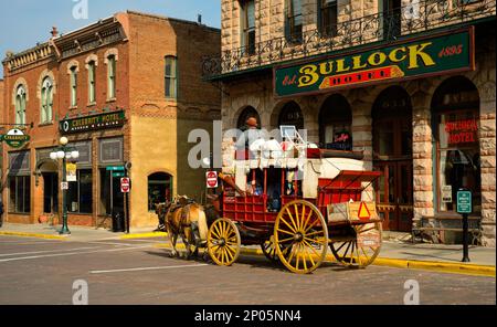 Un vieux stagecoach transporte les touristes devant l'ancien hôtel Bullock sur main St. dans la ville de la ruée vers l'or des Black Hills à Deadwood, Dakota du Sud. Banque D'Images