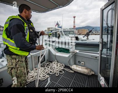 Capitaine d’armes 2nd classe Keenan Martin se prépare à passer une ligne de remorquage à un autre bateau de sécurité portuaire lors d’une simulation de panne mécanique de son embarcation pendant les activités du commandant de la flotte évaluation de la région de Sasebo (CFAS) (SACR), le 15 février 2023. Le SACR fait partie du cycle d’entraînement et de certification du commandant, Marine installations Command (CNIC), de la Force de sécurité de la Marine, qui teste l’intervention et l’état de préparation de la force de sécurité d’une installation. Banque D'Images