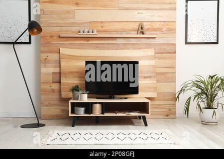 Téléviseur moderne près d'un mur décoratif en bois dans le salon Banque D'Images