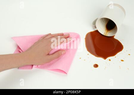 Femme nettoyant le café renversé sur fond blanc, gros plan Banque D'Images