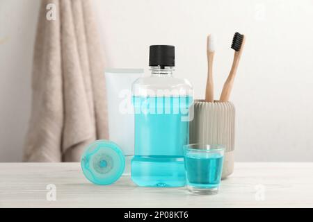 Bain de bouche et autres produits d'hygiène buccale sur une table en bois blanc dans la salle de bains Banque D'Images