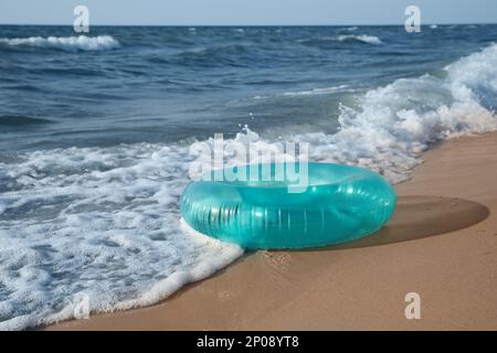 Anneau gonflable lumineux sur la plage de sable près de la mer Banque D'Images