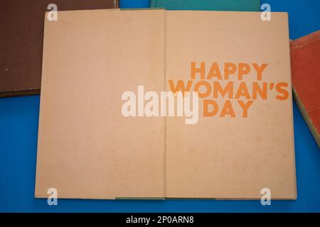 Happy Woman's Day mot dans un livre ouvert avec vintage, des motifs naturels vieux papier design ancien. Banque D'Images