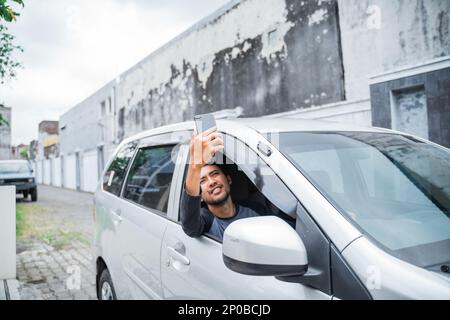 un conducteur de sexe masculin recherche le signal du téléphone cellulaire pendant la conduite Banque D'Images
