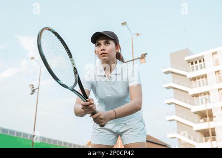 Vue de dessous d'une athlète féminine de tennis se concentrant tenant raquette Banque D'Images