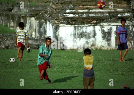 Les enfants jouent au football sur un terrain d'herbe entre les ruines du Palais Kaibon, un patrimoine culturel de la période du Sultanat de Banten situé dans une région appelée Banten Lama (ancienne Banten) à Serang, Banten, Indonésie, sur cette photo prise en 2004. Une étude de terrain menée récemment par Nurikah et E. Rakhmat Jazuli (Faculté de droit, Université Sultan Ageng Tirtayasa, Banten) a révélé qu'il y avait de nombreuses violations contre le traitement des objets du patrimoine culturel dans la région. Les gens "mènent des activités sportives dans l'environnement des objets du patrimoine culturel, par exemple jouer au football sur... Banque D'Images