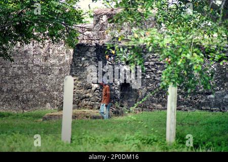 Un homme qui marche sur le terrain de pelouse est un premier plan sur cette photo de 2004 du mur extérieur du fort Speelwijk, un fort hollandais construit sur le territoire du Sultanat de Banten situé dans une région maintenant appelée Banten Lama (ancienne Banten) à Serang, Banten, Indonésie. Une étude de terrain menée récemment par Nurikah et E. Rakhmat Jazuli (Faculté de droit, Université Sultan Ageng Tirtayasa, Banten) a révélé qu'il y avait de nombreuses violations contre le traitement des objets du patrimoine culturel dans la région. Banque D'Images