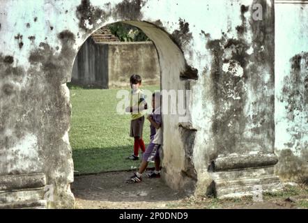 Les enfants portant des apaurels pour jouer au football sont vus à l'entrée d'un mur sur les ruines du palais Kaibon, un patrimoine culturel de la période du Sultanat de Banten situé dans une région appelée Banten Lama (ancienne Banten) à Serang, Banten, Indonésie, sur cette photo prise en 2004. Une étude de terrain menée récemment par Nurikah et E. Rakhmat Jazuli (Faculté de droit, Université Sultan Ageng Tirtayasa, Banten) a révélé qu'il y avait de nombreuses violations contre le traitement des objets du patrimoine culturel dans la région. Les gens "mènent des activités sportives dans l'environnement des objets du patrimoine culturel,... Banque D'Images