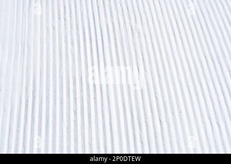 Gros plan de pistes bien entretenues sur une pente dans une station de ski alpin. Lignes droites et rapprochées de pistes de ski fraîchement préparées et soignées Banque D'Images