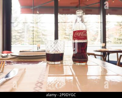 Erevan, Arménie, 28 février 2023: Photo de la boîte de Coca-Cola Classic bouteille de verre et tasse dans le restaurant. Bouteille de Coca-Cola et coca cola en verre. Banque D'Images