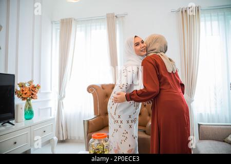 Femme musulmane en voile visitant et embrassant tout en célébrant Eid Banque D'Images