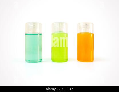 Trois petites bouteilles en plastique pleines de produits cosmétiques colorés avec espace de copie. Produits de soins du corps et de beauté pour le bain en récipients vierges - douche ge Banque D'Images