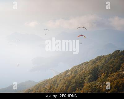 Parapente dans le ciel. Tandem de parapente volant au-dessus de la mer et des montagnes par jour nuageux. Vue sur le parapente et le lagon bleu à Oludeniz, Turquie. Sport extrême. Paysage Banque D'Images