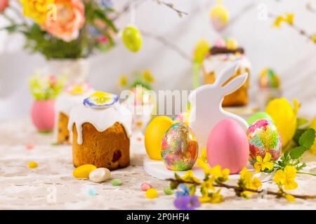 Pâques encore vie avec des gâteaux de Pâques colorés, des œufs de Pâques sur une assiette de dessert de lapin. Un cadeau de Pâques traditionnel sur une table de fête décorée de flo printanier Banque D'Images