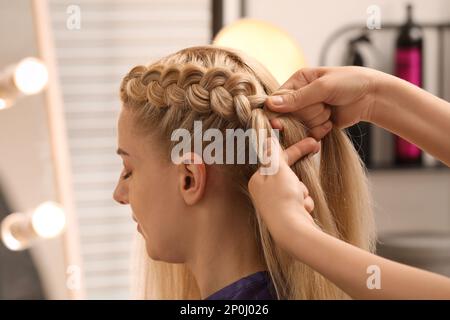 Un styliste professionnel brase les cheveux du client en salon Banque D'Images