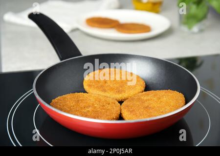 Cuisson des côtelettes panées dans une poêle Banque D'Images