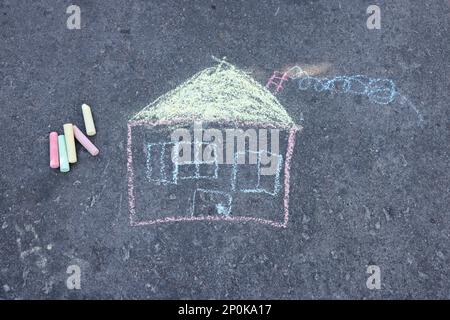 Dessin de maison d'enfant et morceaux de craie de couleur sur l'asphalte, plat Banque D'Images