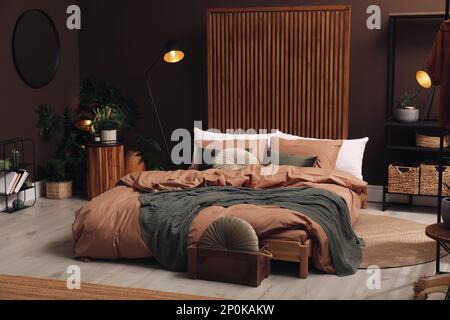 Chambre élégante avec grand lit près d'un mur brun Banque D'Images