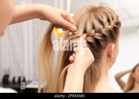 Un styliste professionnel brase les cheveux du client en salon Banque D'Images