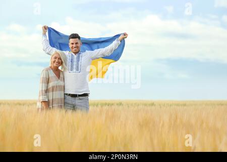 Homme avec mère portant le drapeau national de l'Ukraine sur le terrain. Espace pour le texte Banque D'Images