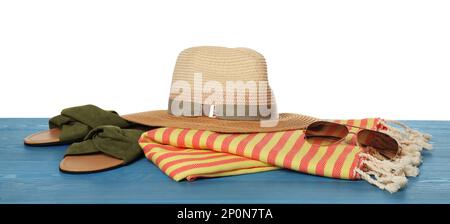 Serviette de plage, pantoufles, chapeau de paille et lunettes de soleil sur une surface en bois bleu clair sur fond blanc Banque D'Images