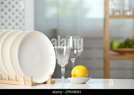 Nettoyez les assiettes dans le panier à vaisselle, les verres et le citron sur la table blanche à l'intérieur Banque D'Images