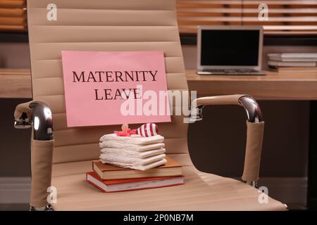 Accessoires de soins pour bébés, carnets et note avec texte congé de maternité sur chaise de bureau à l'intérieur Banque D'Images
