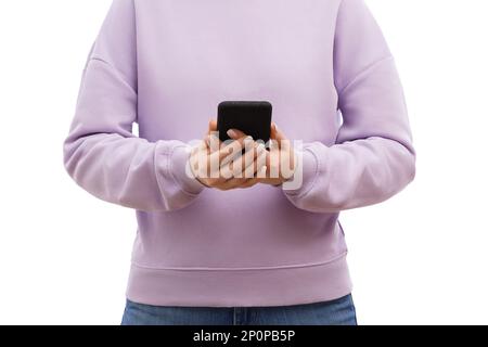 Coupe courte d'une femme dans un chandail de lavande et un Jean tient le smartphone avec les deux mains. Banque D'Images