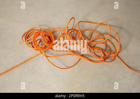 Cordon électrique orange emmêlé, concept de problème impossible Banque D'Images