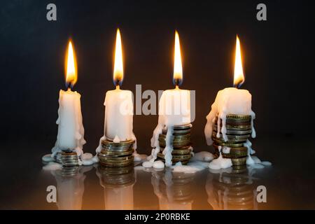 bougies blanches qui brûlent sur les piles de pièces, sur fond sombre. Plus d'argent, moins de métaphore de la vie Banque D'Images