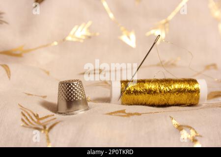 Bobine de fil d'or avec Thimble sur tissu de mousseline métallique Banque D'Images