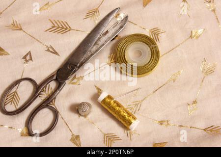 Bobine de fil d'or et ciseaux avec filet sur tissu de mousseline métallique Banque D'Images