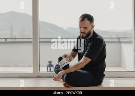 Jeune homme pratiquant un auto-massage avec appareil de massage corporel pour se détendre à la maison Banque D'Images