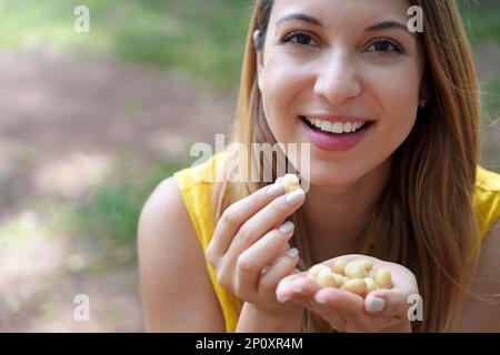 Gros plan de la fille en bonne santé cueillant des noix de macadamia en plein air. Regarde la caméra. Banque D'Images