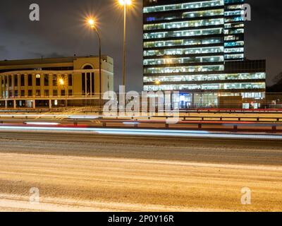 lumière des voitures qui passent sur une route enneigée de la ville en hiver Banque D'Images