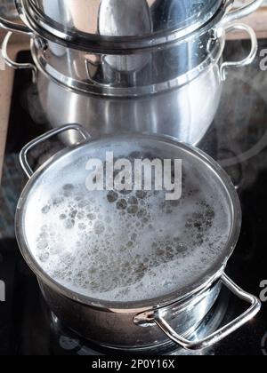 l'eau bout dans une casserole sur une cuisinière en céramique dans la cuisine maison Banque D'Images