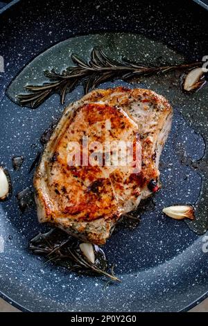 Steak de bœuf de qualité supérieure grillé dans la poêle, steak de cuisson dans la cuisine sur fond sombre. Plan supérieur du chef préparant la ribeye avec du beurre, Banque D'Images