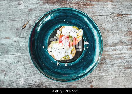 Toast à l'avocat avec œufs brouillés sur la plaque bleue de la table en bois. Nourriture saine pour le petit déjeuner Banque D'Images