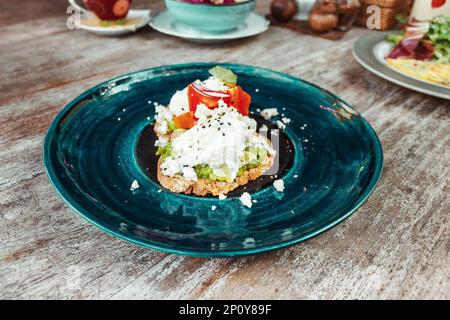 Toast à l'avocat avec œufs brouillés sur la plaque bleue de la table en bois. Nourriture saine pour le petit déjeuner Banque D'Images