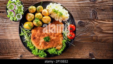 Côtelettes panées de porc enrobées de chapelure servie avec des pommes de terre et du chou Banque D'Images