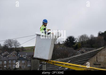 Entrepreneur en télécommunications avec équipement de sécurité approprié travaillant à partir d'un préparateur de cerisier pour installer une nouvelle ligne téléphonique domestique dans le West Yorkshire, au Royaume-Uni Banque D'Images