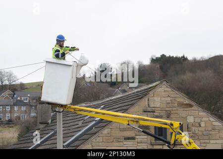 Entrepreneur en télécommunications avec équipement de sécurité approprié travaillant à partir d'un préparateur de cerisier pour installer une nouvelle ligne téléphonique domestique dans le West Yorkshire, au Royaume-Uni Banque D'Images