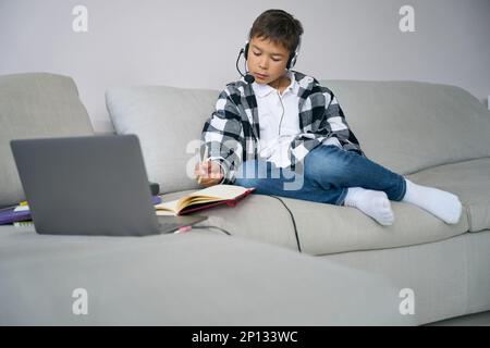 Garçon est sur la formation en ligne dans un environnement confortable à la maison Banque D'Images