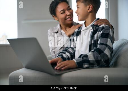 La mère bienveillante aide son fils dans l'apprentissage en ligne Banque D'Images