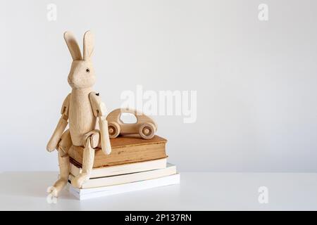 Encore plus de vie avec un lièvre en bois sur charnières à l'intérieur. Une pile de livres et une voiture en bois pour enfants. Banque D'Images